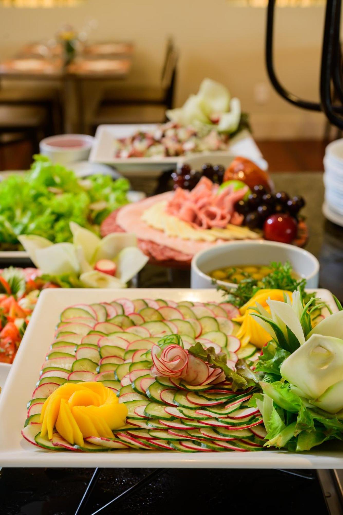 Hotel Luzeiros Fortaleza Exterior photo The photo showcases a beautifully arranged display of food. In the foreground, there's a plate with thinly sliced cucumbers arranged in a decorative pattern, garnished with leafy greens and edible flowers. Surrounding this plate are various other dis